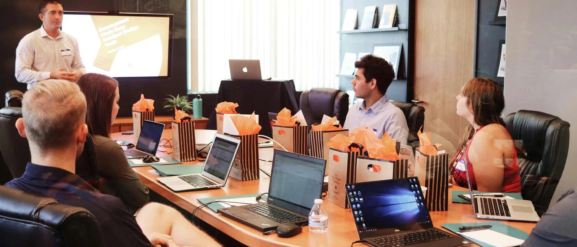 A team seated around a conference table with laptops during a presentation