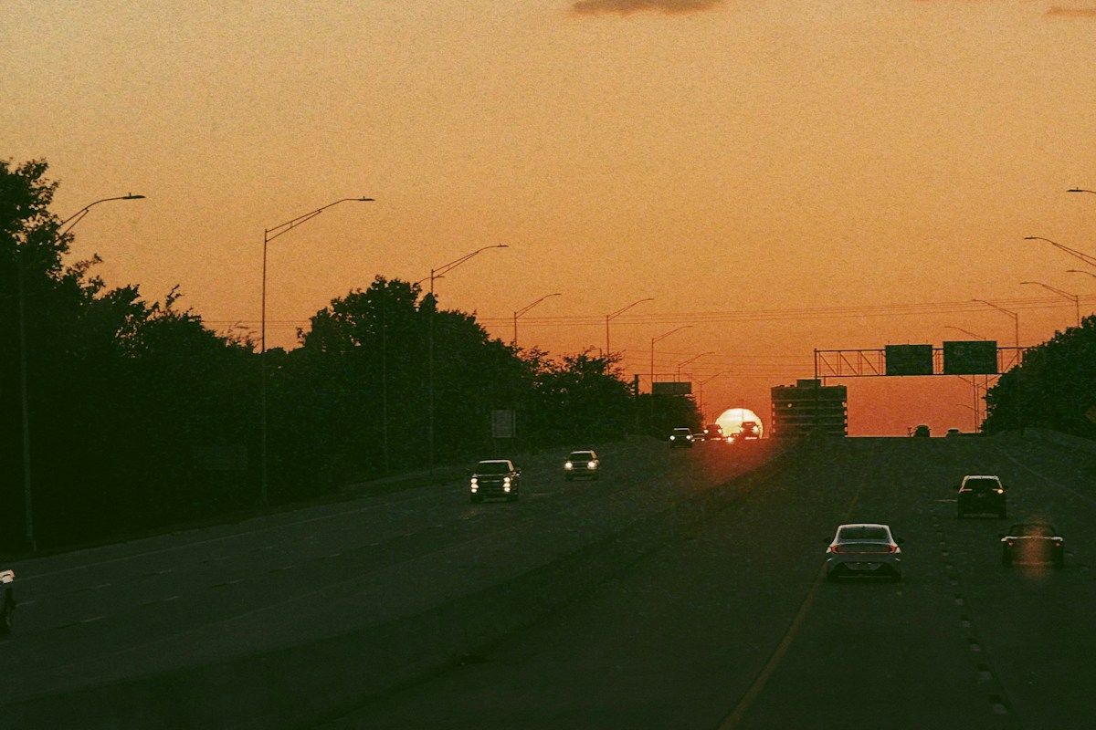 Cars on a divided highway under a dusk sky