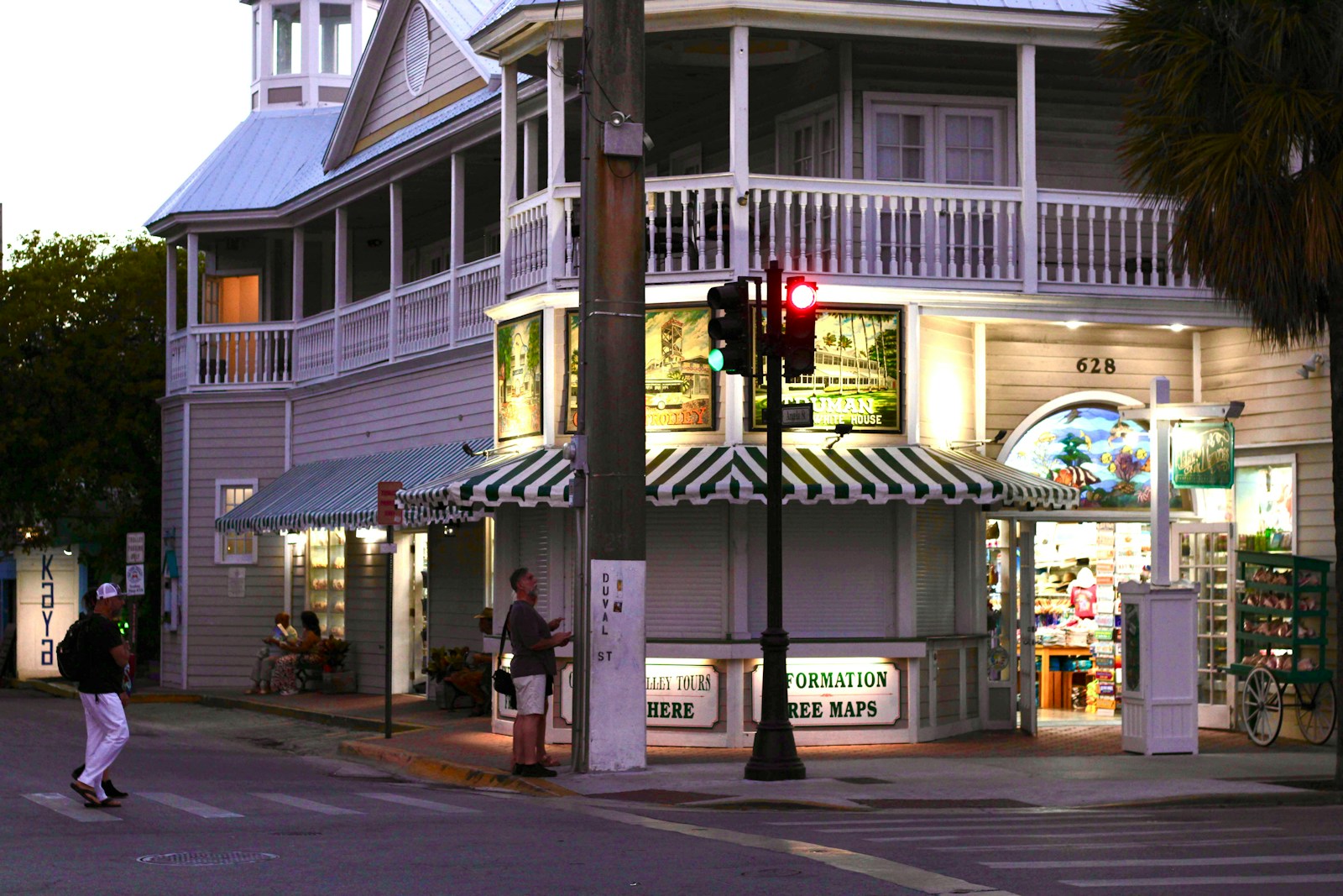 A corner storefront with awnings and pedestrians at dusk