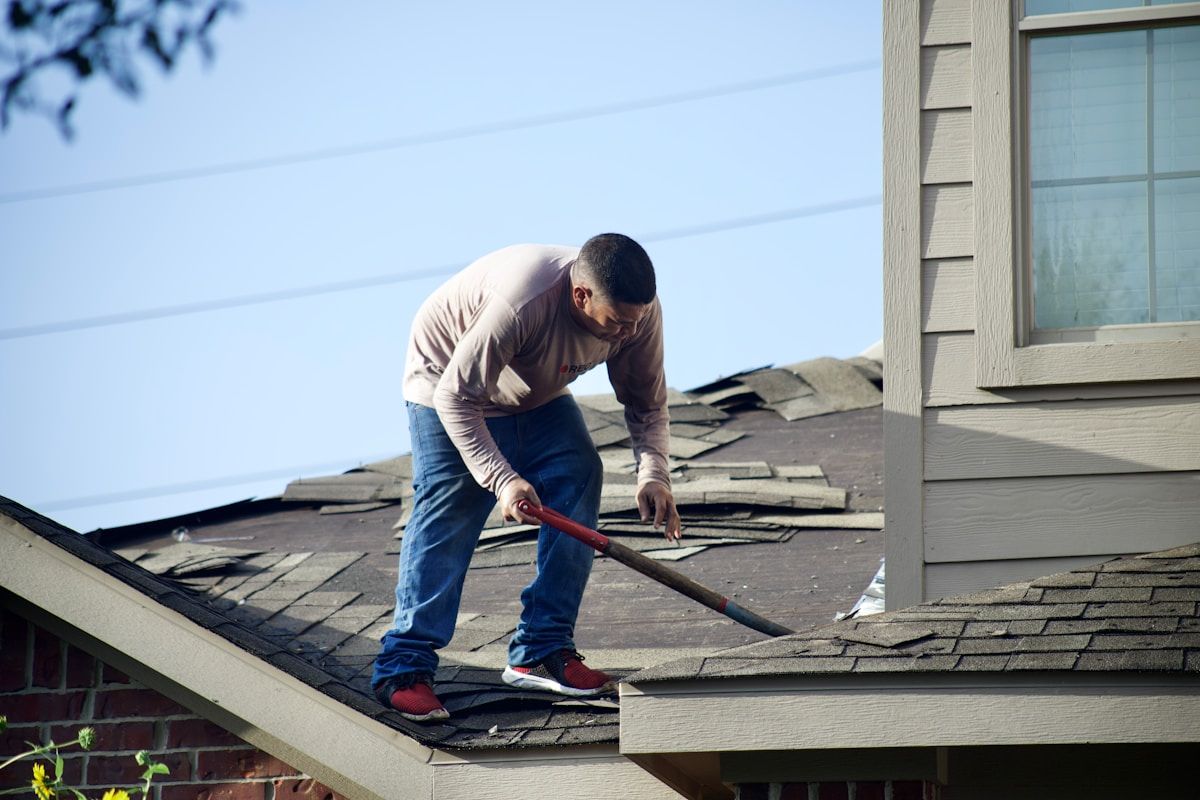 A worker repairing the shingles on a house roof