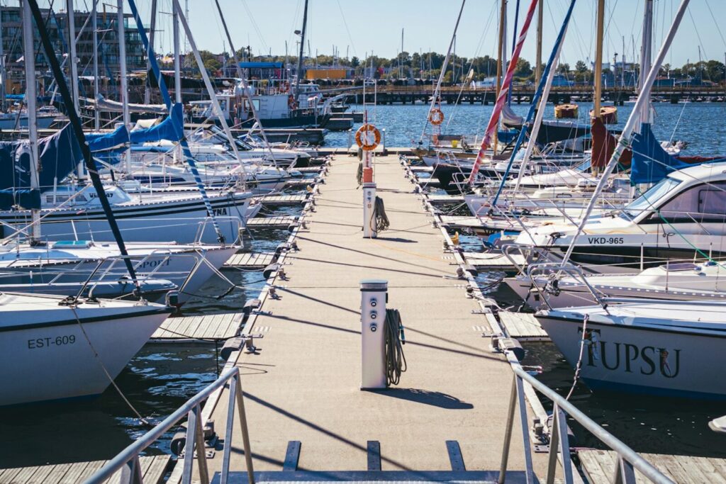 Sailing boats moored either side of a marina pontoon on a clear day