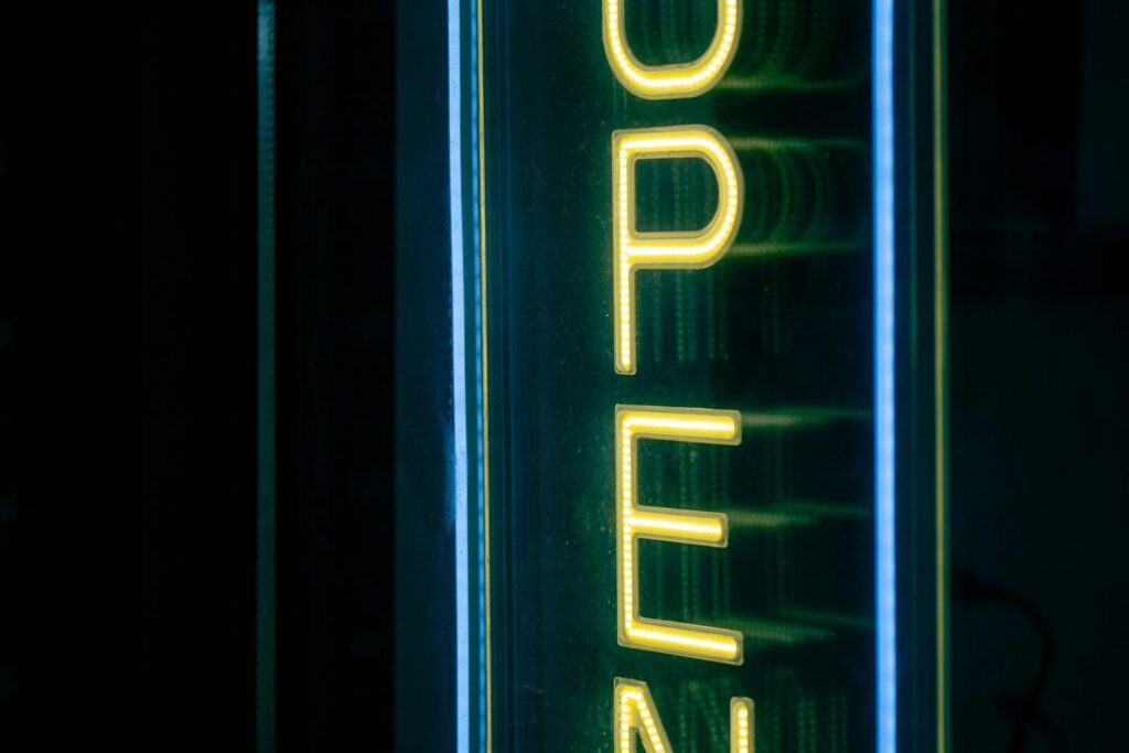 Un letrero de neón vertical que dice OPEN encendido en la vitrina de un local