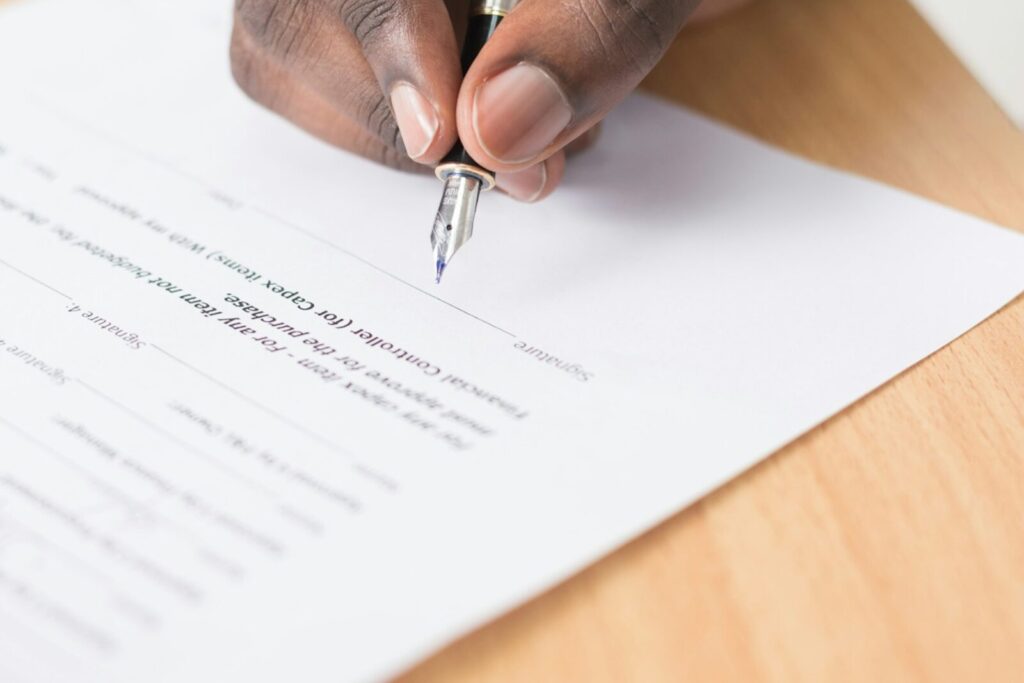 Una mano firmando un documento impreso con una pluma fuente