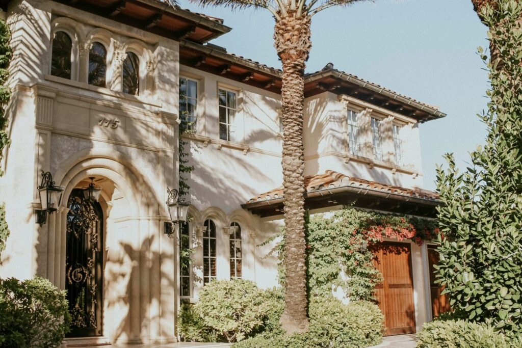 A Mediterranean-style Florida home behind palms and mature planting