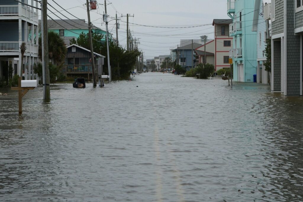 A residential coastal street under standing water up to the doorsteps