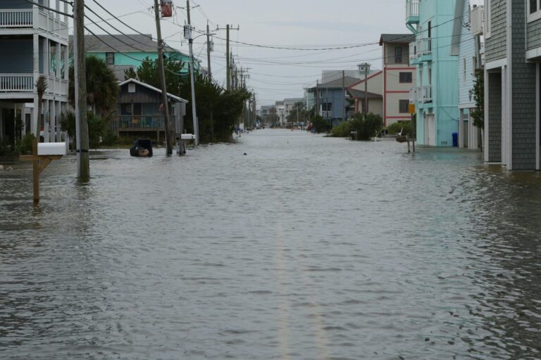 A residential coastal street under standing water up to the doorsteps