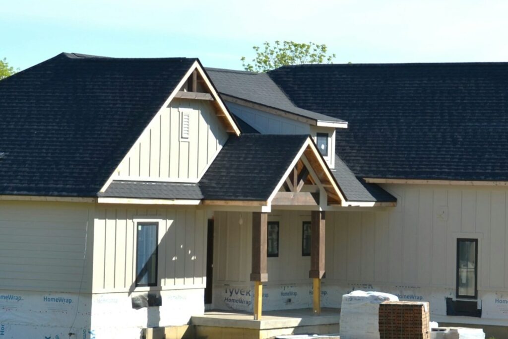 A new house under construction with a dark shingle roof and gabled porches