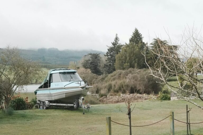 A boat sitting on a trailer at the edge of a field